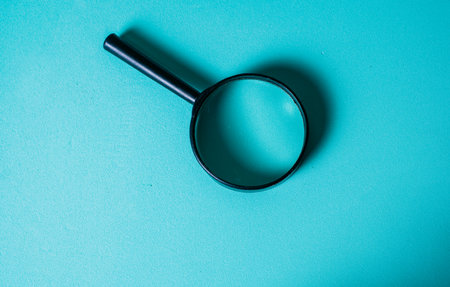 Magnifying Glass on Teal Background for Investigation Concept. CloseUp of Magnifying Glass for Search and Discovery Themeの写真素材