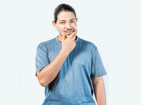 Pensive person rubbing chin with doubtful expression. Thoughtful young man rubbing his chin looking at camera isolatedの写真素材