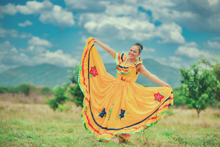 Hispanic girl in national folk costume in a field smiling at cameraの写真素材