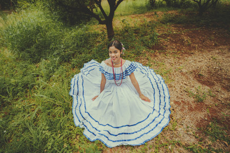 Smiling woman wearing traditional Nicaraguan folk costume sitting on the grassの写真素材