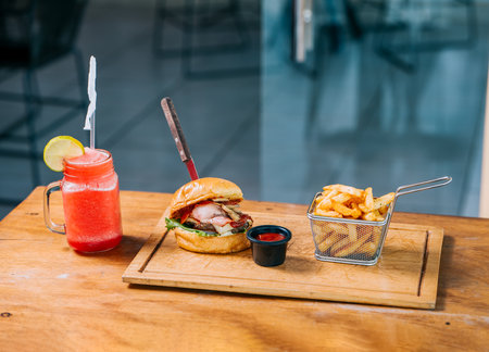 Big beef burger with fries and refreshing drink served on wooden tableの写真素材