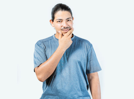 Pensive person rubbing chin with doubtful expression. Thoughtful young man rubbing his chin looking at camera isolatedの写真素材