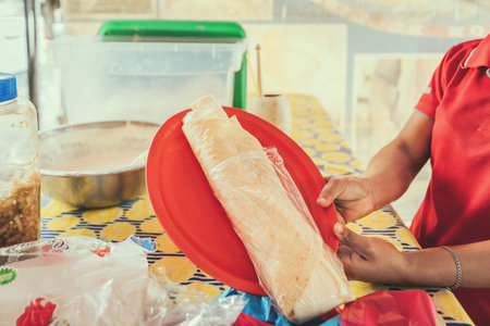 Hands of a person serving traditional quesillo. Vendor serving delicious quesillo in a bagの写真素材