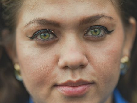 Close up of Latin American girl face looking and smiling at the camera. Portrait of attractive latin girl smiling outdoorsの写真素材