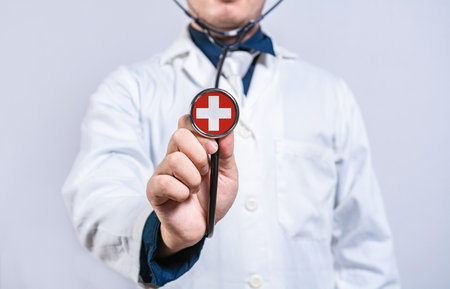 Doctor hands holding stethoscope with Switzerland flag. Switzerland health and care conceptの写真素材