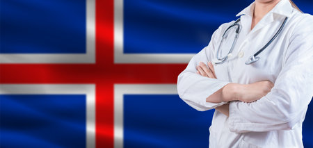 Doctor with crossed arms on Iceland flag. Iceland health and care concept. Female doctor on Iceland flagの写真素材
