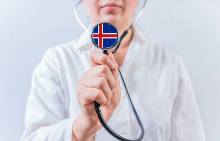 Female doctor holding stethoscope with Iceland flag. National health system of Icelandの写真素材
