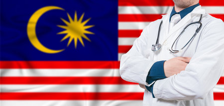 Malaysia healthcare concept. Male doctor on Malaysia flag. Doctor with crossed arms on Malaysia flagの写真素材