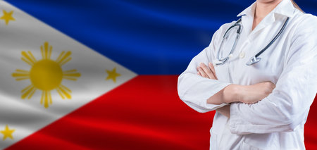 Doctor with crossed arms on Philippines flag. Philippines health and care concept. Female doctor on Philippines flagの写真素材