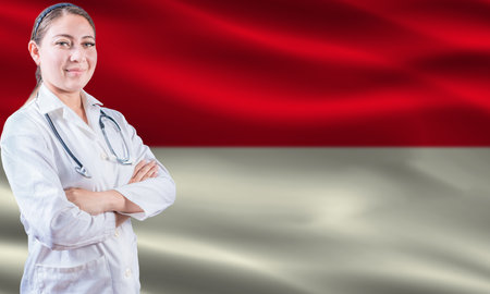Female doctor on Indonesia flag. Doctor with crossed arms on Indonesia flag. Indonesia health and care conceptの写真素材