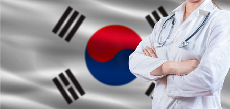 Doctor with crossed arms on South Korea flag. South Korea health and care concept. Female doctor on South Korea flagの写真素材