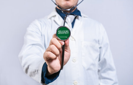 Doctor hands holding stethoscope with Saudi Arabia flag. Saudi Arabia health and care conceptの写真素材