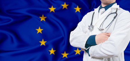 European Union healthcare concept. Male doctor on European Union flag. Doctor with crossed arms on European Union flagの写真素材