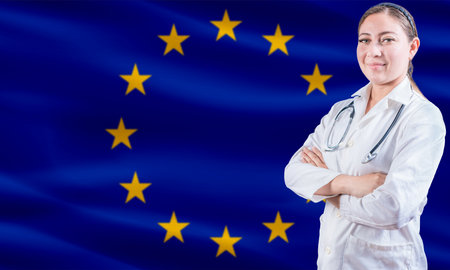 Female doctor on European Union flag. Doctor with crossed arms on European Union flag. EU health and care conceptの写真素材