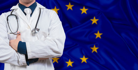 Male doctor with stethoscope on European Union flag. Doctor holding stethoscope on European Union flagの写真素材