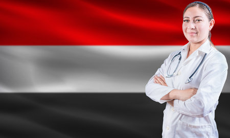 Female doctor on Yemen flag. Doctor with crossed arms on Yemen flag. Yemeni health and care conceptの写真素材