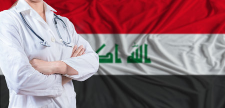 Doctor with crossed arms on Iraq flag. Iraq health and care concept. Female doctor on Iraq flagの写真素材