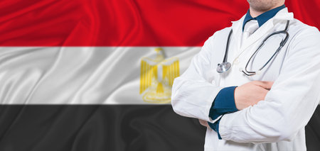 Egypt healthcare concept. Male doctor on Egypt flag. Doctor with crossed arms on Egypt flagの写真素材
