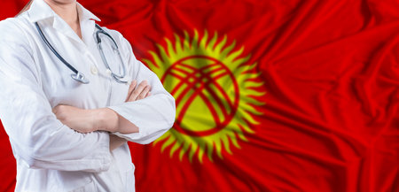 Doctor with crossed arms on Kyrgyzstan flag. Kyrgyzstan health and care concept. Female doctor on Kyrgyzstan flagの写真素材
