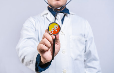 Doctor hands holding stethoscope with Bhutan flag. Bhutan health and care concept}の写真素材
