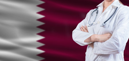 Doctor with crossed arms on Qatar flag. Qatar health and care concept. Female doctor on Qatar flagの写真素材
