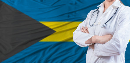 Doctor with crossed arms on Bahamas flag. Bahamas health and care concept. Female doctor on Bahamas flagの写真素材