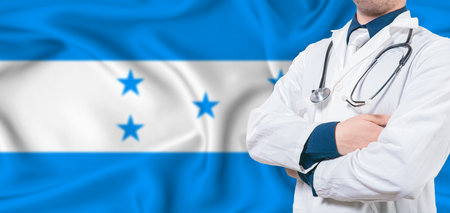 Honduras healthcare concept. Male doctor on Honduras flag. Doctor with crossed arms on Honduras flagの写真素材