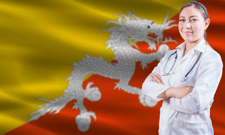 Female doctor on Bhutan flag. Doctor with crossed arms on Bhutan flag. Bhutan health and care conceptの写真素材