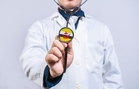 Doctor hands holding stethoscope with Brunei flag. Brunei health and care conceptの写真素材