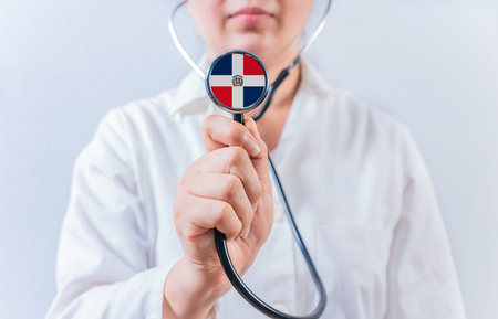 Female doctor holding stethoscope with Dominican Republic flag. National health system of Dominican Republicの写真素材