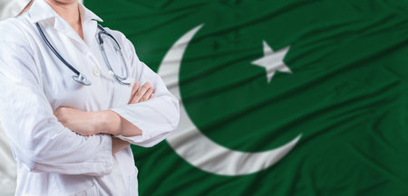 Doctor with crossed arms on Pakistan flag. Pakistani health and care concept. Female doctor on Pakistan flagの写真素材