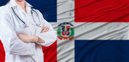 Doctor with crossed arms on Dominican Republic flag. Dominican health and care concept. Female doctor on Dominican Republic flagの写真素材