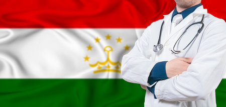 Tajikistan healthcare concept. Male doctor on Tajikistan flag. Doctor with crossed arms on Tajikistan flagの写真素材