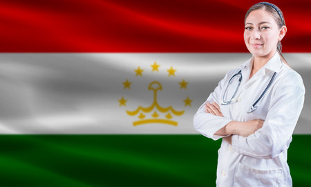Female doctor on Tajikistan flag. Doctor with crossed arms on Tajikistan flag. Tajikistan health and care conceptの写真素材