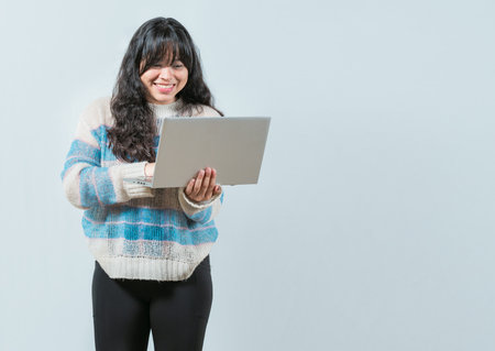 Smiling asian girl holding and looking on laptop screen isolated. Portrait of beautiful asian woman using and looking at laptopの写真素材