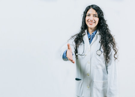 Smiling female doctor gesturing welcome, isolated. Latin female doctor shaking hands at the camera gesturing welcomeの写真素材