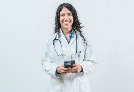 Young doctor holding phone, Concept of online medical services. Smiling female doctor using smart phone isolatedの写真素材