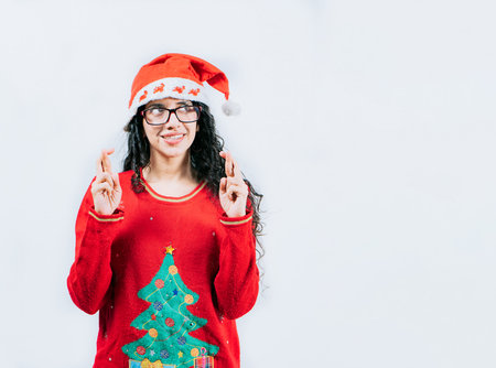 Young woman in Christmas sweater making a wish and crossing fingers. Beautiful girl in Christmas sweater making a wish isolatedの写真素材