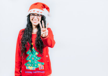 Smiling girl in Christmas sweater counting number 3. Happy girl in Christmas hat counting number THREE, isolatedの写真素材