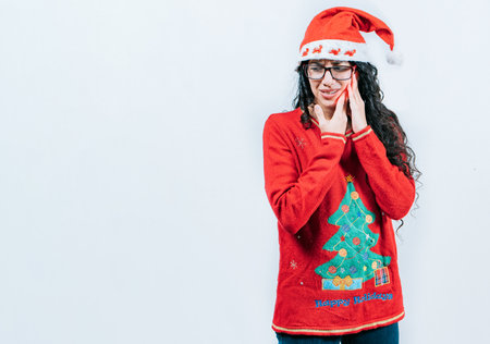 Girl in Christmas dress with toothache on isolated background. Young girl with toothache holding her cheek in Christmas dressの写真素材