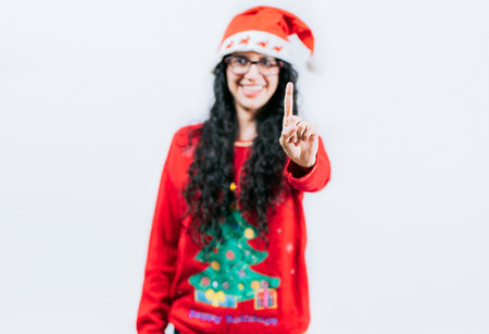 Happy girl in Christmas hat counting number ONE, isolated. Smiling girl in Christmas sweater counting number 1の写真素材