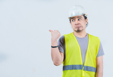 Funny construction worker pointing at an isolated blank space. Surprised builder pointing at an...