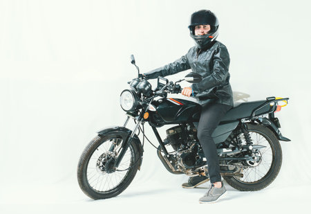 Male motorcyclist riding his motorcycle on isolated background. Smiling young man riding a...