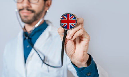 Doctor holding stethoscope with United Kingdom flag. United Kingdom health and care concept, United Kingdom flag on stethoscopeの写真素材