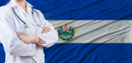 Doctor with crossed arms on El Salvador flag. El Salvador health and care concept. Female doctor on El Salvador flagの写真素材