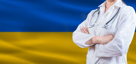 Doctor with crossed arms on Ukraine flag. Ukraine Health and Care concept. Female doctor on Ukraine flagの写真素材