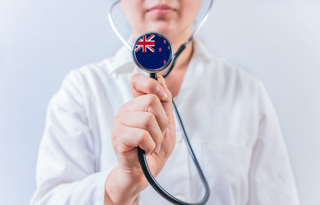 Female doctor holding stethoscope with New Zealand flag. National health system of New Zealandの写真素材