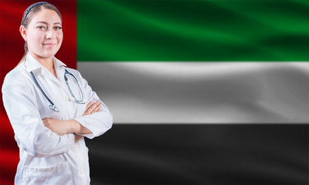 Female doctor on United Arab Emirates flag. Doctor with crossed arms on United Arab Emirates flag. United Arab Emirates health and care conceptの写真素材