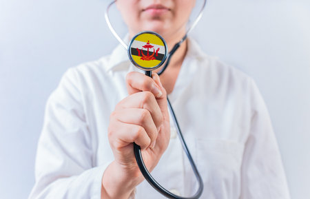 Female doctor holding stethoscope with Brunei flag. National health system of Bruneiの写真素材