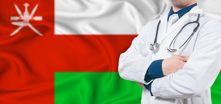 Oman healthcare concept. Male doctor on Oman flag. Doctor with crossed arms on Oman flagの写真素材